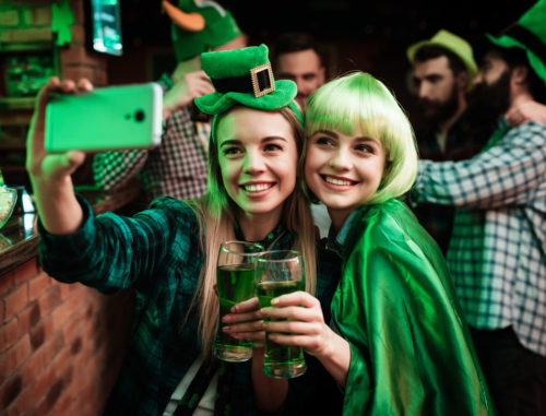 Two girls in a wig and hat make selfi at the bar.