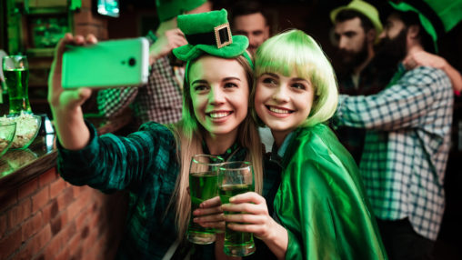 Two girls in a wig and hat make selfi at the bar.